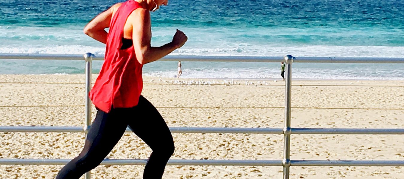 running-at-the-beach-young-and-fit-millennial-woman-in-a-red-top-and-high-hair-bun-running-along-the_t20_1bNNbg